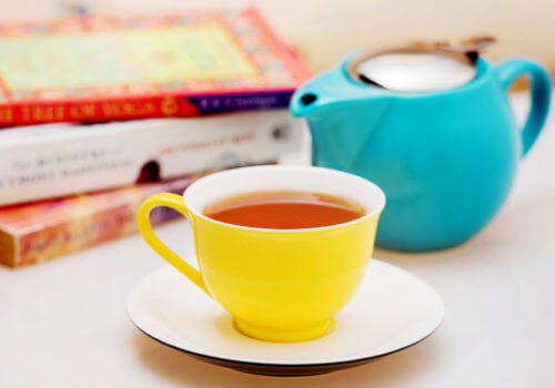 Blue teapot and yellow cup of tea with books